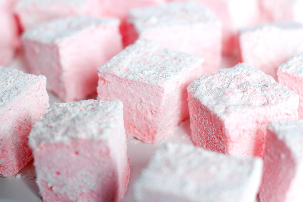 a batch of pale pink homemade strawberries and champagne marshmallows coated in powdered sugar.