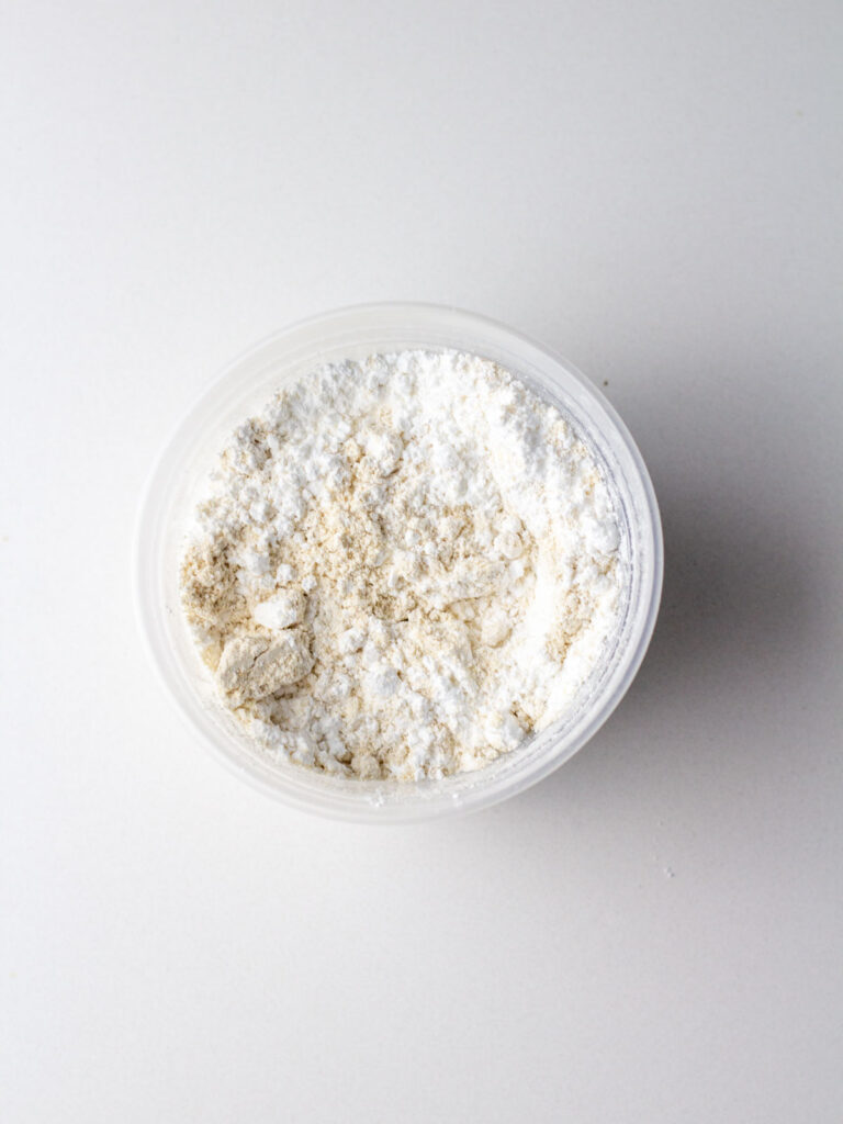 Oat flour and powdered sugar combined in a small clear container.