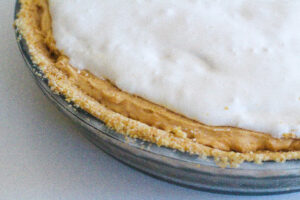 Close up of the layers of a fluffernutter pie - bread crumb crust, peanut butter pie filling, marshmallow fluff topping