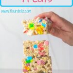 A pin for Pinterest of a hand placing a fourth lucky charms treat on a stack of three cereal bars.