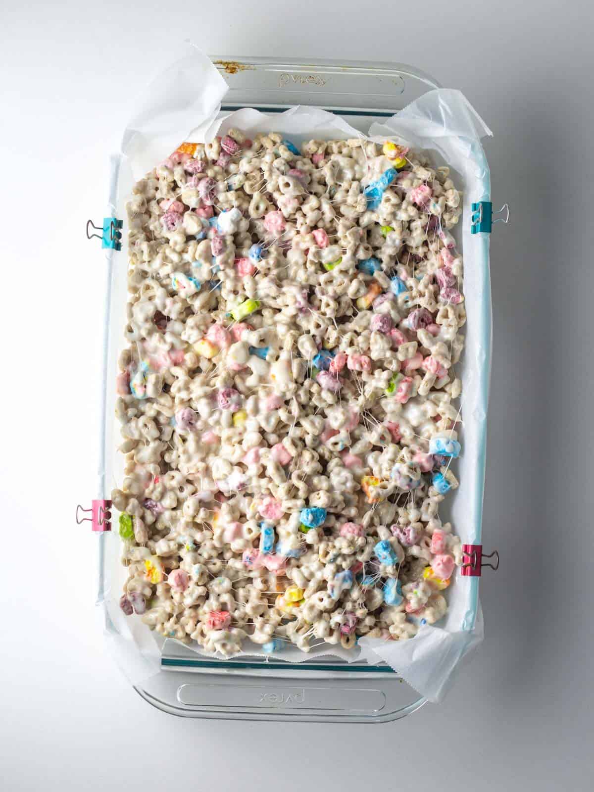 The cereal marshmallow mixture pressed into the 9x13 parchment lined glass pan.