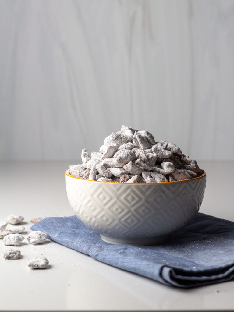 An overflowing bowl of cinnamon toast crunch puppy chow on a blue napkin.