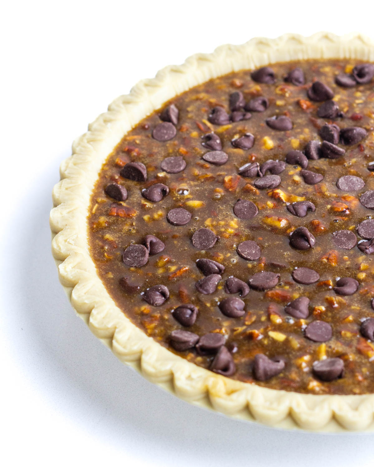 Half of an unbaked maple bourbon chocolate pecan pie with the other half going out of frame.