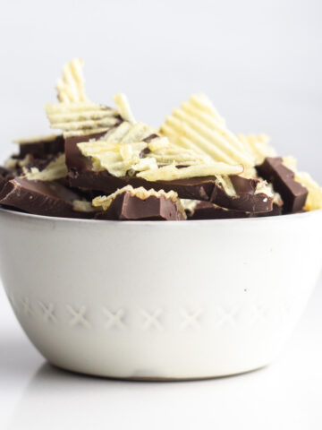 A white bowl filled with potato chip topped chocolate bark.