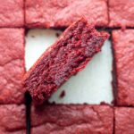 A sliced batch of red velvet brownies with the center brownie sideways to show the inside.