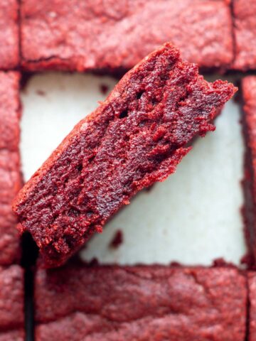 A sliced batch of red velvet brownies with the center brownie sideways to show the inside.