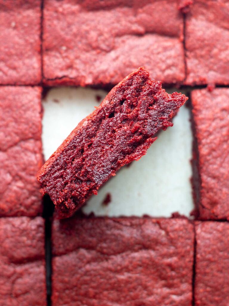 A sliced batch of red velvet brownies with the center brownie sideways to show the inside.