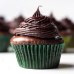 Close up of a chocolate mint cupcake with more cupcakes blurred in the background.