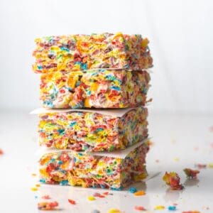 A stack of 4 Fruity Pebbles Bars each separated by a square of parchment paper.