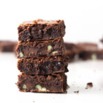 Stack of four Chocolate Thin Mint Brownies with additional brownies blurred in the background.