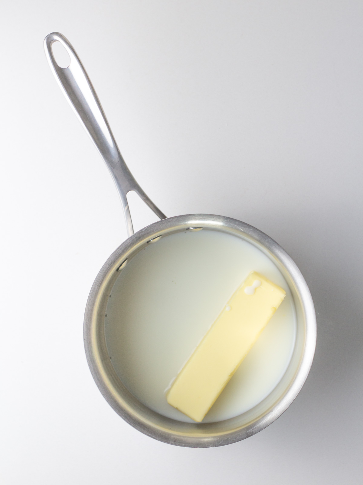 Milk and a stick of butter in a small silver saucepan.