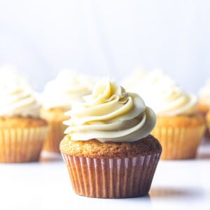 A frosted maple cupcake in front of the rest of the batch of maple cupcakes.