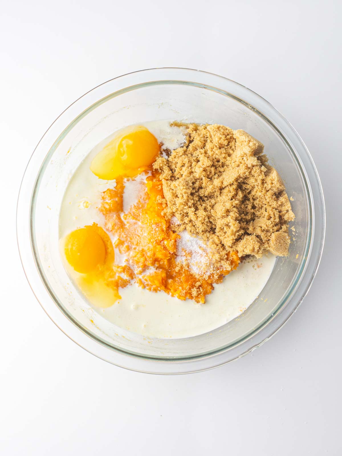 Sweet potato pie filling ingredients in a clear glass mixing bowl.