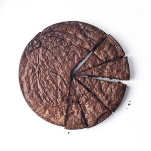 A round flourless chocolate cake with 5 slices cut, but not yet removed from the rest of cake.