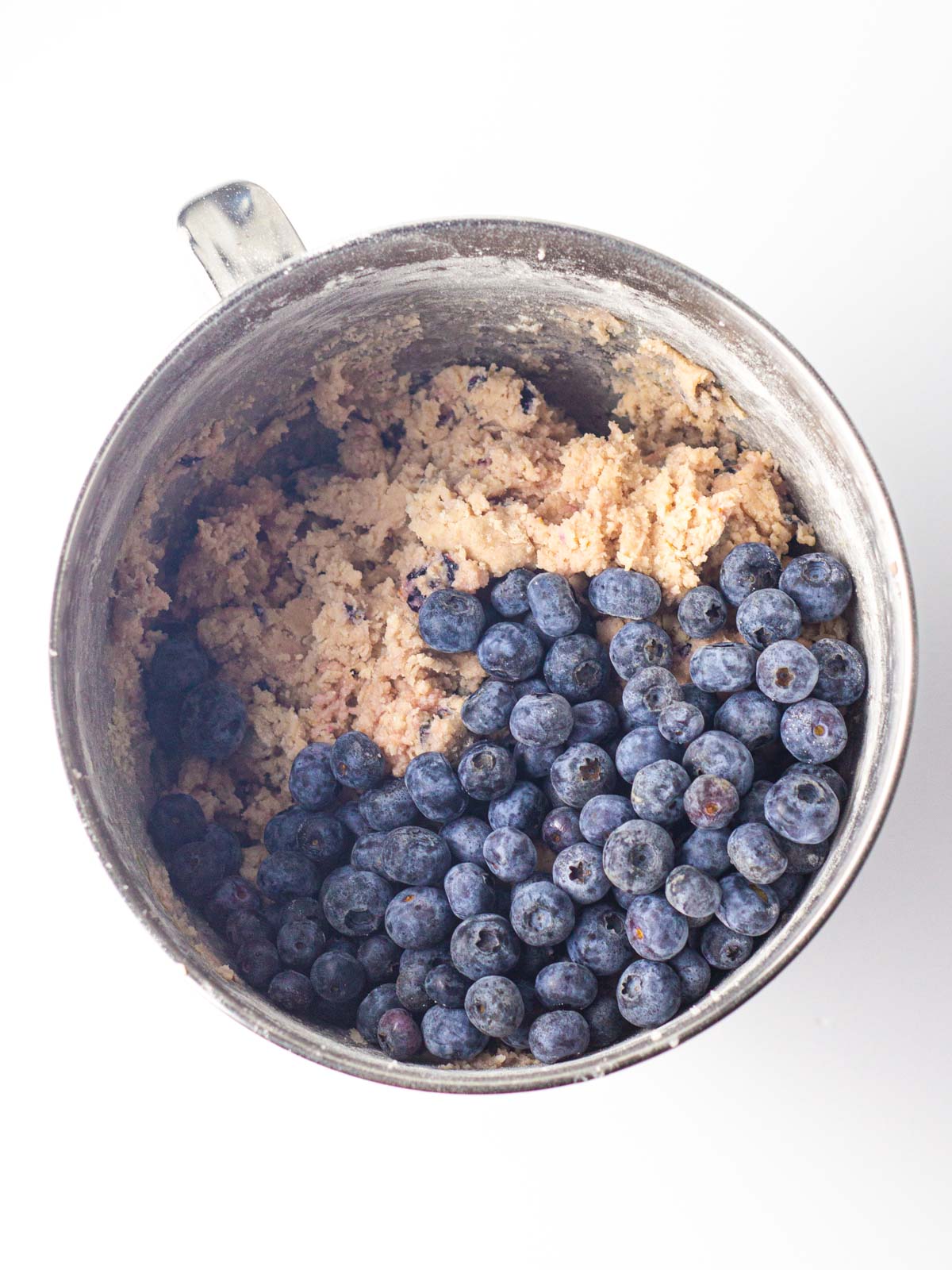 Fresh blueberries on top of the blueberry cookie dough in the silver mixing bowl.