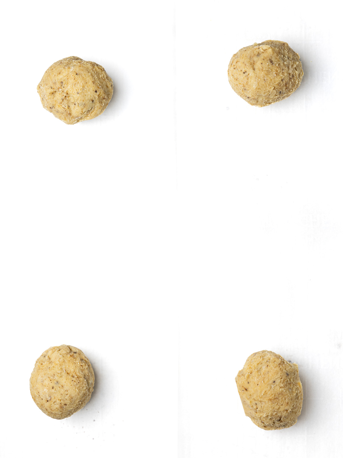 Balls of creme egg cookie dough on a parchment lined baking sheet.