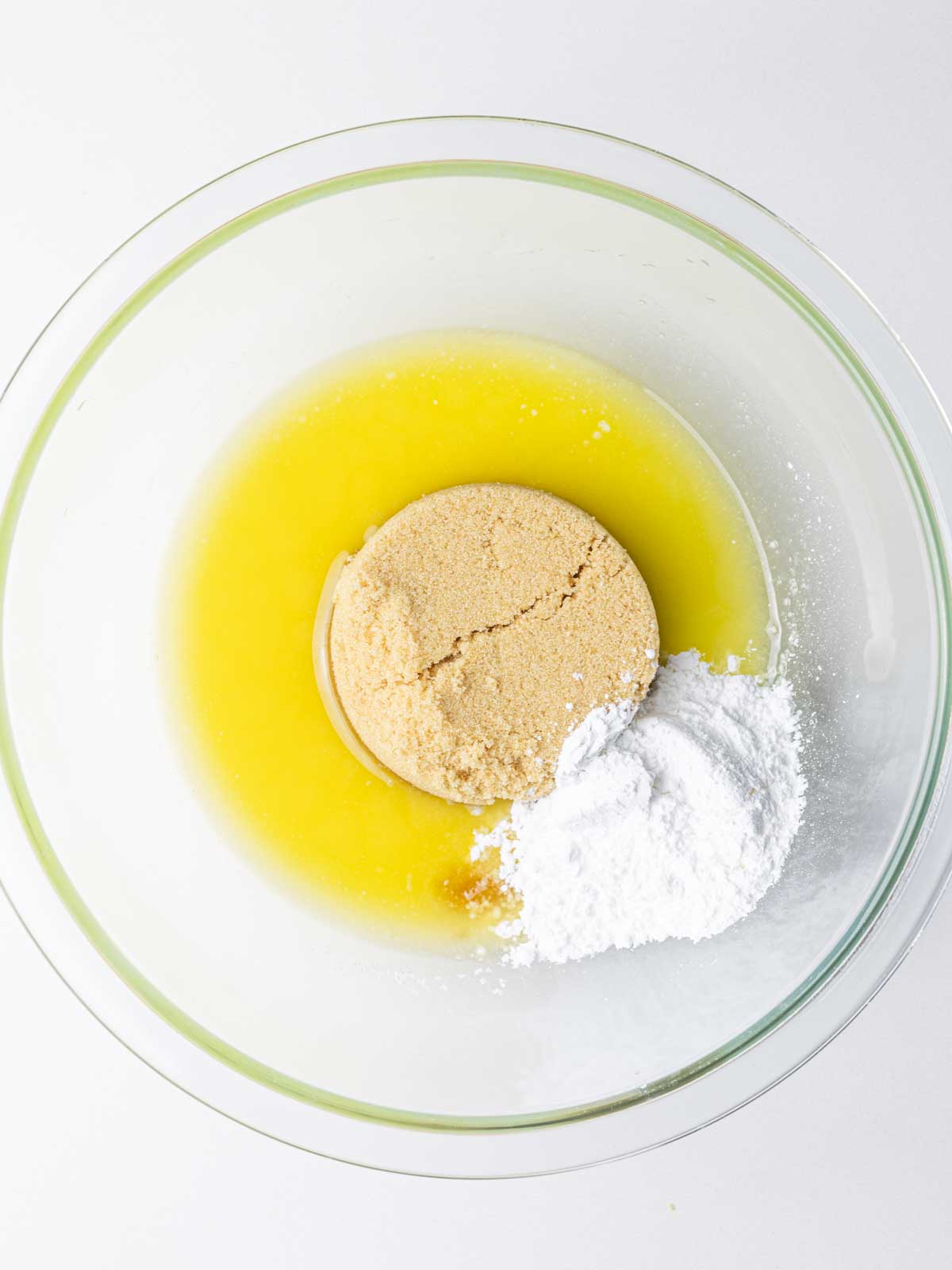 Brown sugar, powdered sugar, and melted butter in a clear glass mixing bowl.