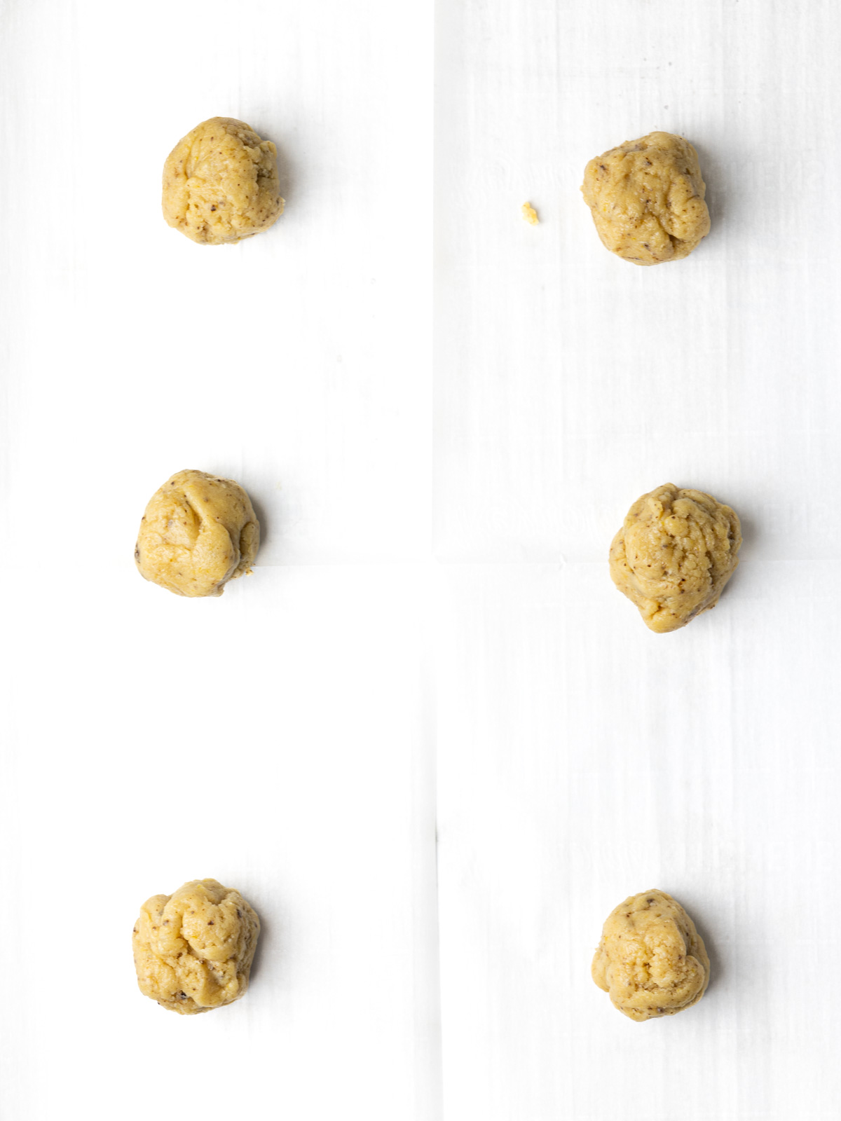 Balls of chocolate chipless cookie dough on a parchment lined baking sheet.