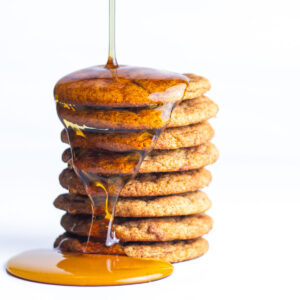 A stack of french toast cookies with maple syrup drizzling on to the stack.