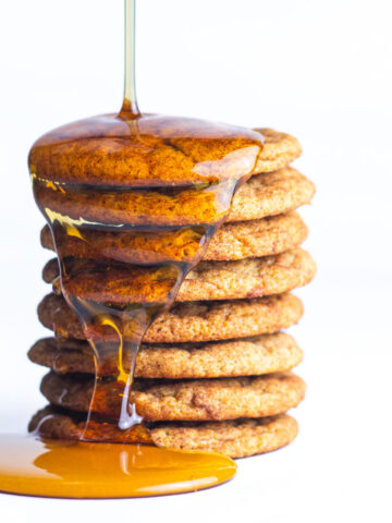A stack of french toast cookies with maple syrup drizzling on to the stack.